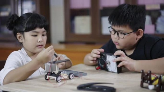 一组男孩和女孩的构建和研究机器人STEM编程软件和修复