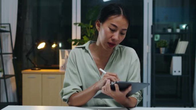 亚洲女商人在预防病毒的新常态下保持社交距离在办公室晚上工作时向同事介绍有关视频通话计划的摄像机演示。