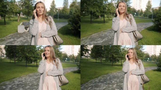 快乐的未来妈妈在夏日的城市公园里用手机说话