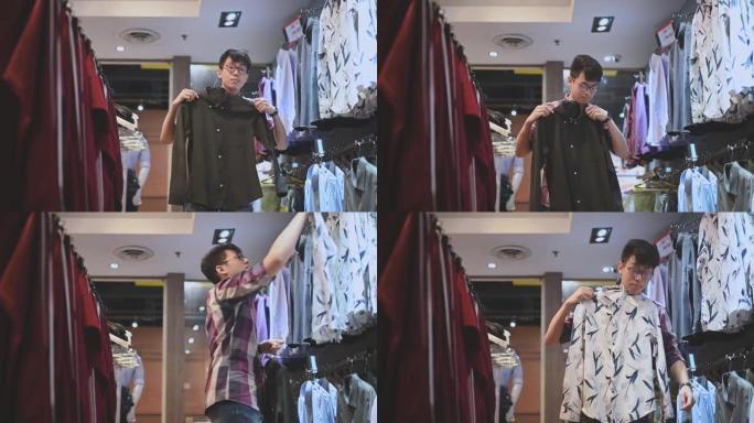 亚洲中国男性手持男装衬衫在服装店选择合适的购物
