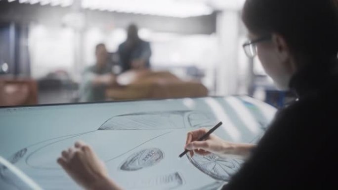由汽车设计师，建模师和工程师组成的团队致力于在工作室中创建具有未来感的汽车。女性在数字平板电脑上绘制