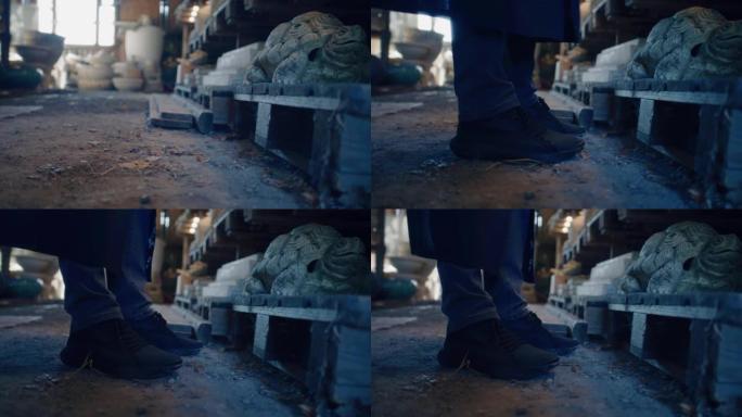 男性陶瓷陶工鞋特写镜头朝着泥塑工作室的架子移动
