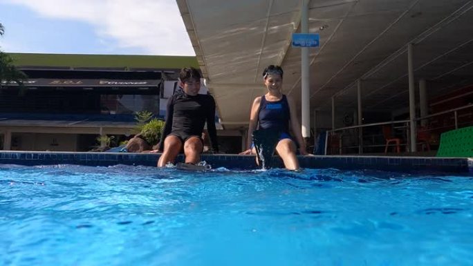 池畔的亚洲中国成熟女性与教练一起用潜水鳍翻水
