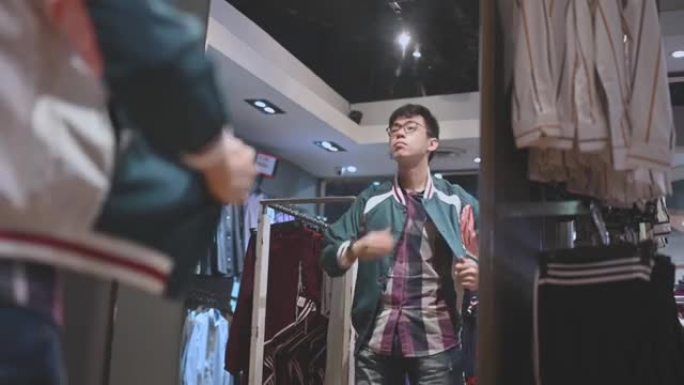 亚洲中国男性手持男装衬衫在服装店尝试选择合适的购物方式