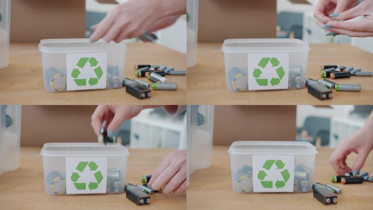 女性手将旧废旧电池放在家里带有回收符号的容器中