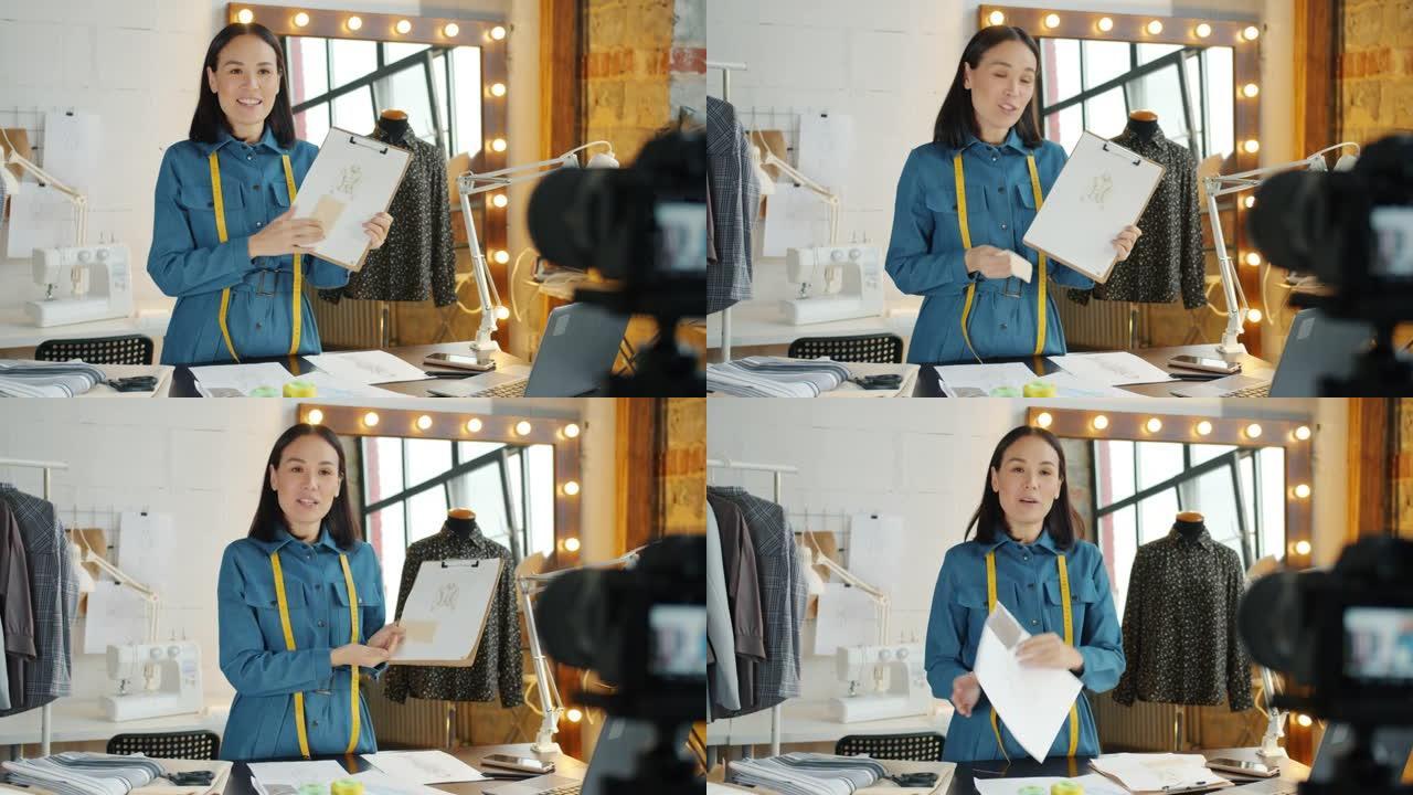 年轻女性视频记录器在制衣工作室录制视频，演讲和展示草图