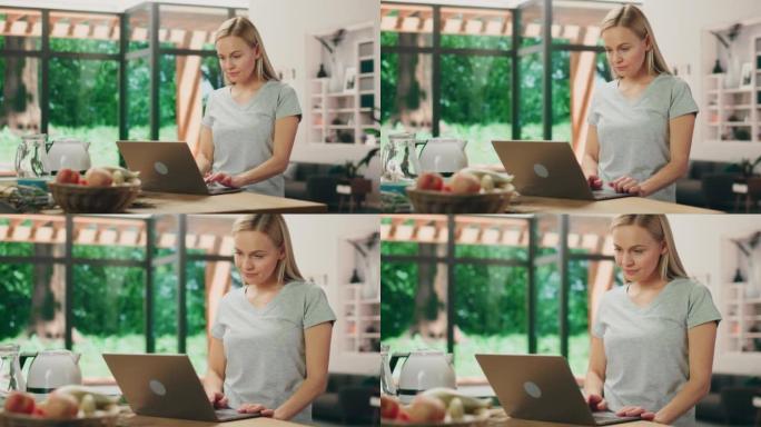 美丽的年轻成年女性肖像，金发碧眼，穿着灰色v领t恤，站在客厅时使用笔记本电脑。在光明公寓在家工作的成