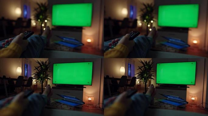 女士无法辨认的女人通过色度键绿屏扫描电视上的不同电视频道