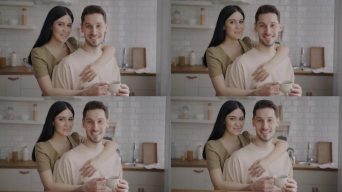 男人和女人站在厨房里抱着咖啡杯微笑的慢动作肖像