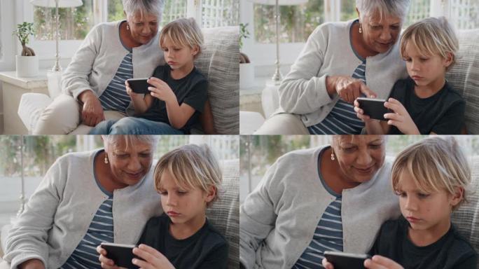 快乐的小男孩使用智能手机展示奶奶如何使用手机教学奶奶现代技术智能孩子在家帮助奶奶4k