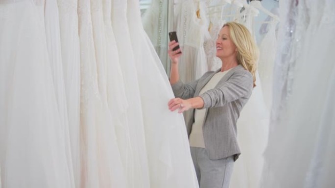新娘商店里的成熟女人翻看婚纱在手机上拍照 -- 慢动作拍摄