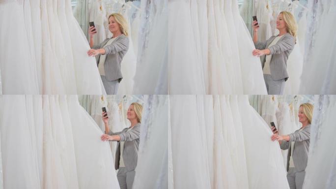 新娘商店里的成熟女人翻看婚纱在手机上拍照 -- 慢动作拍摄