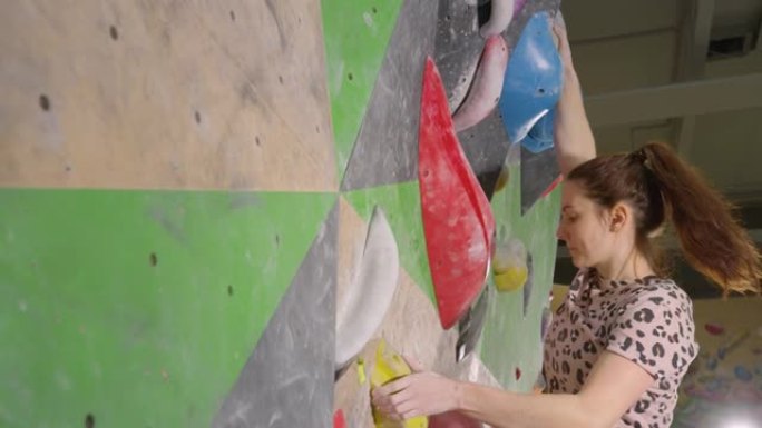特写: 运动女子在攀岩健身房中攀登具有挑战性的路线。