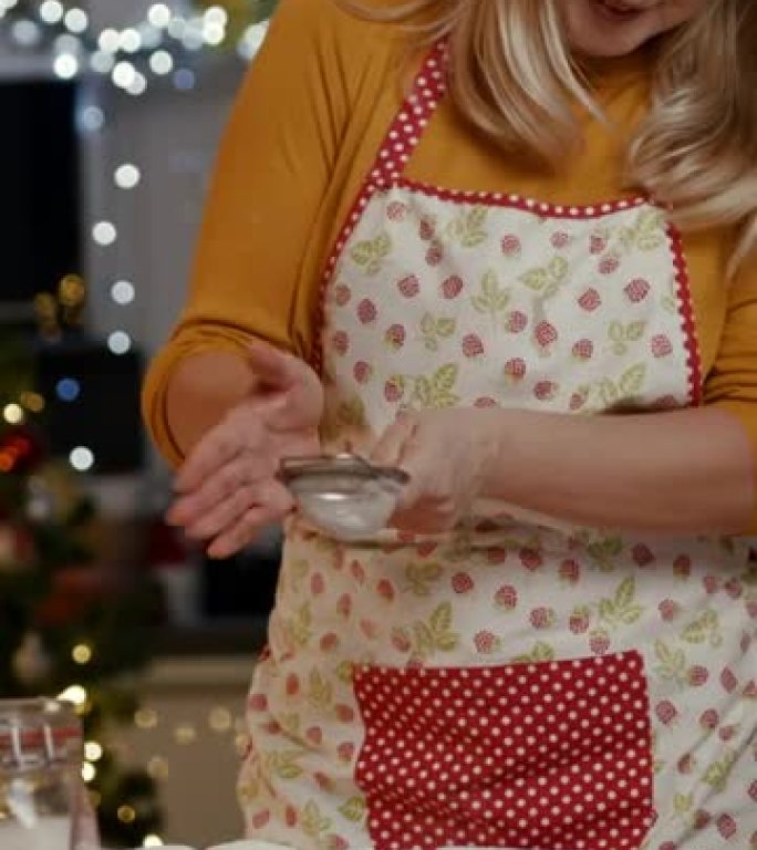 女人在厨房里用糖粉洒和装饰新鲜出炉的饼干上
