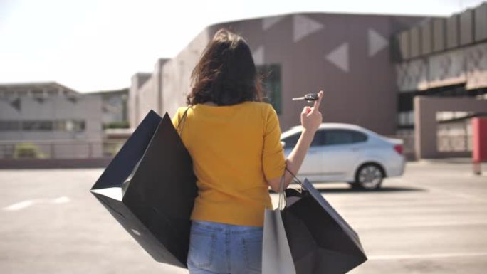 购物日的亚洲妇女在购物中心购物后带着购物袋步行去汽车