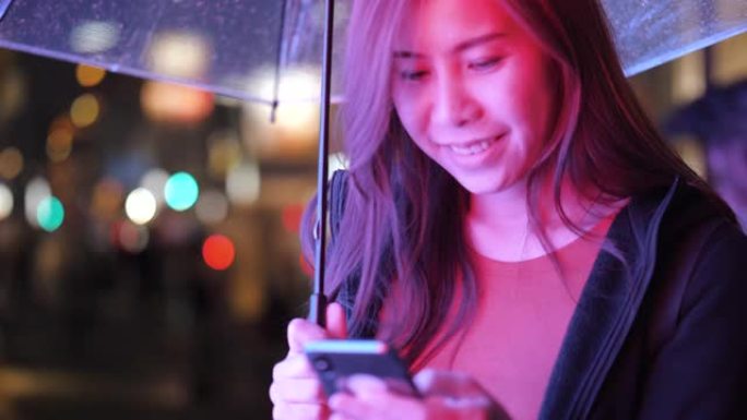 年轻的亚洲妇女在雨中使用电话
