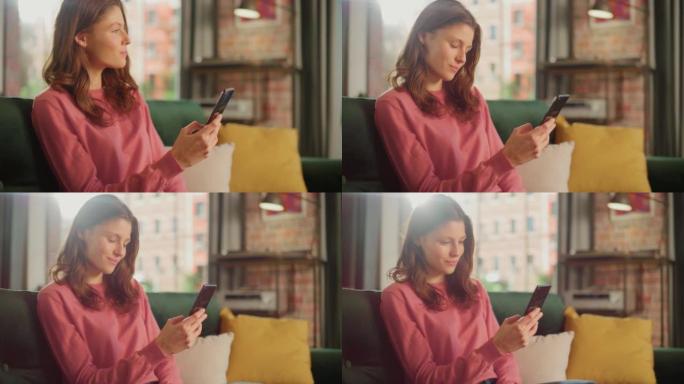 年轻漂亮的女性坐在客厅的沙发上，放松和使用智能手机。创意女孩检查社交媒体，与朋友聊天，浏览互联网。从