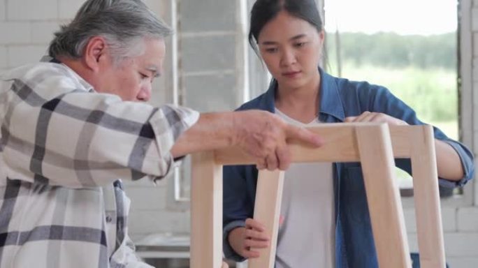 工人木工高级男子年龄70岁和十几岁的女孩一起在工厂里制作木制家具。工厂和制造概念。