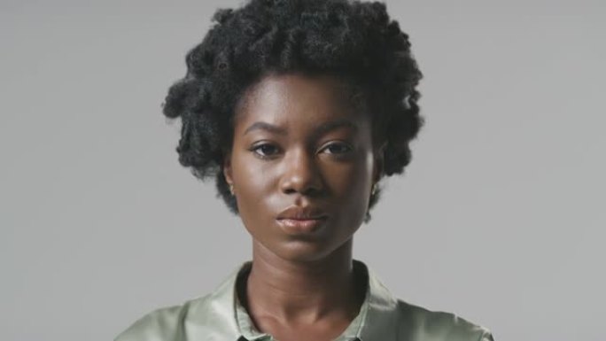 严肃的年轻女商人在普通背景下转向镜头的工作室肖像