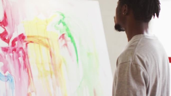体贴的非裔美国男艺术家坐在艺术工作室看着他的画