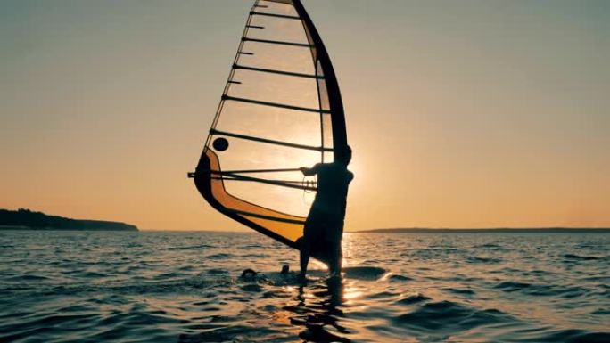 一名男子在日落时漂浮着管理帆板