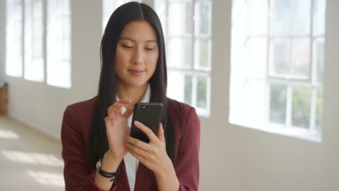亚洲女商人在社交媒体上研究想法，在手机上发短信。企业家独自站立并使用技术进行网络，浏览互联网并与客户