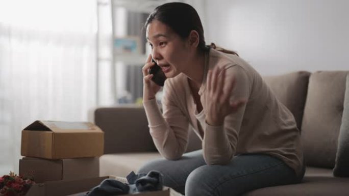 亚洲女性消费者感觉不好坐在沙发上，在网上与商店联系，询问家里有问题的产品订单，电话投诉。