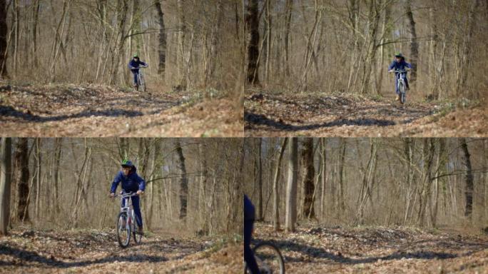 戴着头盔的男孩在秋天的森林小径上骑自行车