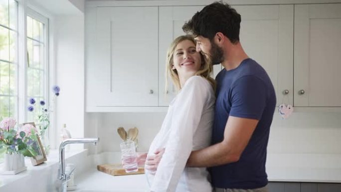 一对男人抱着穿着睡衣的孕妇站在厨房里抱着肿块