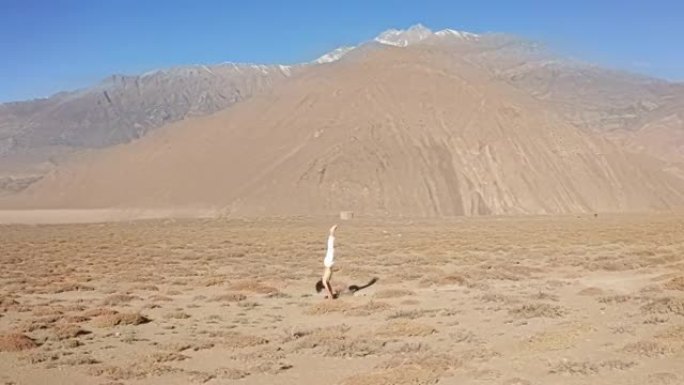尼泊尔男子在沙漠中倒立和蝎子姿势