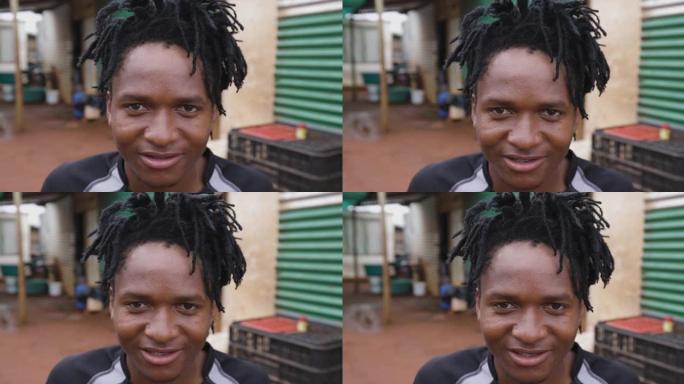 贫穷。不平等。一个黑人非洲男子在贫民窟周围用发辫看着相机的特写肖像。