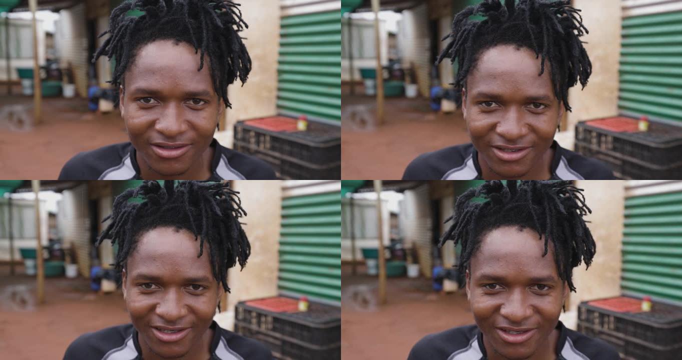 贫穷。不平等。一个黑人非洲男子在贫民窟周围用发辫看着相机的特写肖像。