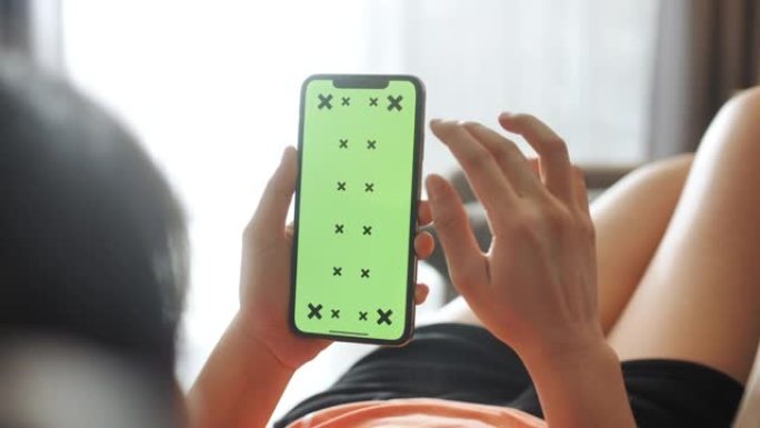 特写绿屏模板智能手机在女性手放在家里的沙发上