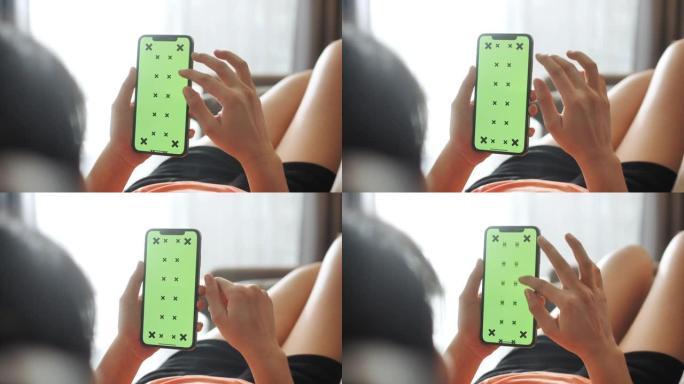 特写绿屏模板智能手机在女性手放在家里的沙发上