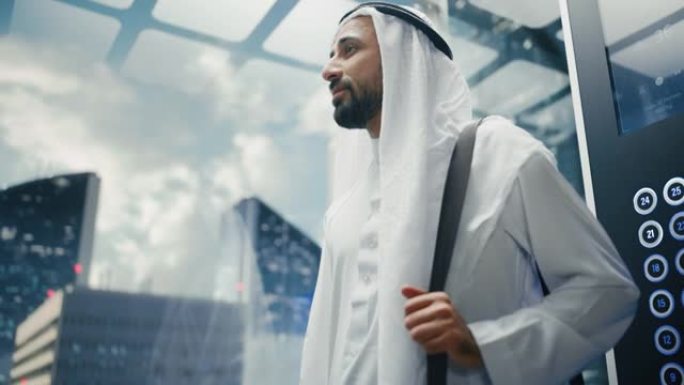 成功的快乐穆斯林商人在传统的白色坎杜拉骑玻璃电梯到现代商务中心的办公室。沙特、阿联酋、阿拉伯商人概念