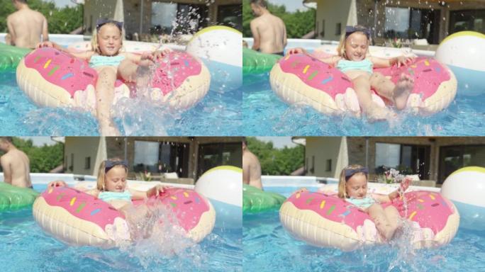 关闭小女孩一边泼水，一边漂浮在游泳池里的漂浮甜甜圈上