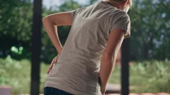 一名年轻的成年女性在家中从沙发上站起来，并因脊柱创伤而感到背部疼痛。按摩和伸展背部以减轻不适和伤害。