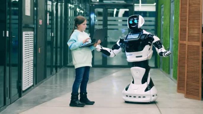 小女孩用笔记本电脑操作机器人。未来主义技术概念。