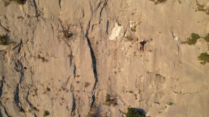 空中: 攀岩者配备了绳索，沿着阳光普照的石灰岩墙上升