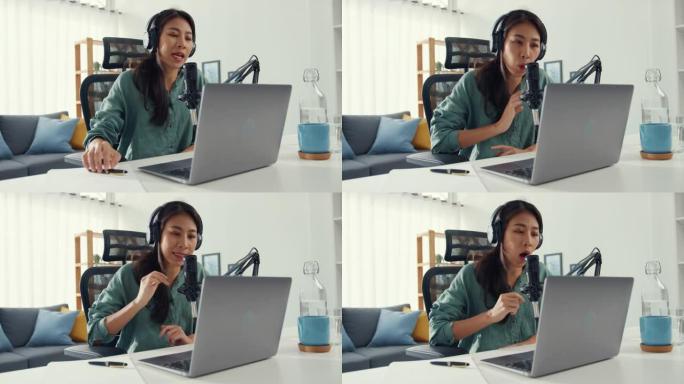 快乐亚洲女孩用耳机和麦克风在她的笔记本电脑上录制播客，并在她的房间里与观众交谈。