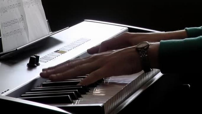 一个年轻女子弹电子琴的手。特写。