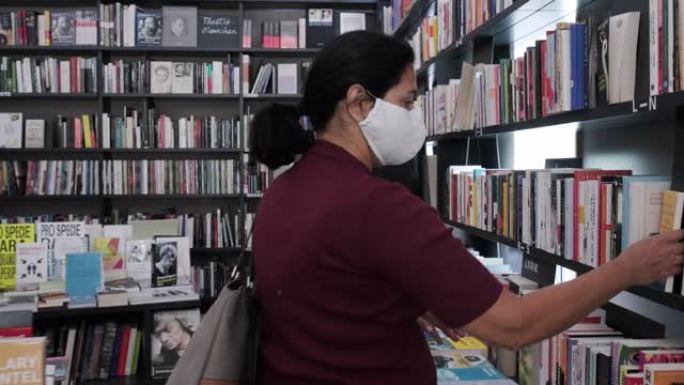 戴口罩的成熟女人选择在书店购买的书籍