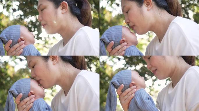 母亲抱着孩子，早上在公园用爱亲吻
