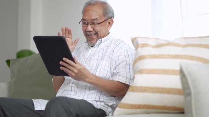 祖父在家中客厅的数字平板电脑上给孙子孙女打视频电话