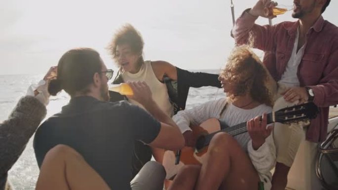 SLO MO女人在帆船甲板上向一群朋友弹吉他
