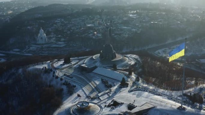 在阳光明媚的寒冷冬日，基辅光荣的独立乌克兰国旗和祖国纪念碑的高角度航拍。