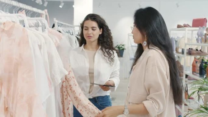 友好的女售货员在时装店与卖衣服的女顾客交谈