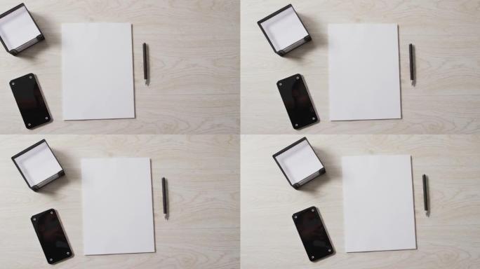 木制背景上的智能手机和白纸的视频，带有笔和复印空间