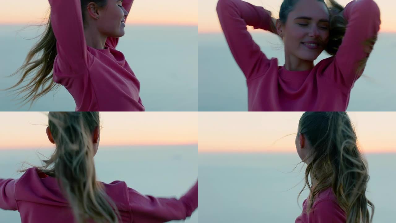 快乐的女人在山顶上跳舞，享受自由庆祝成就女孩日落时看着美丽的海景