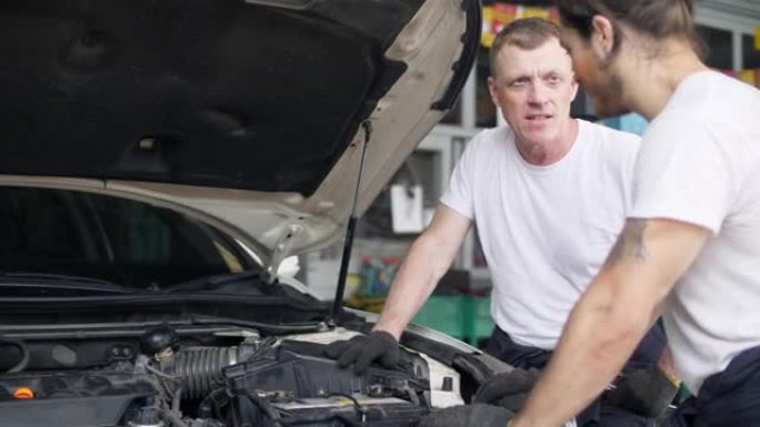 两名机械师在汽车修理厂检查汽车